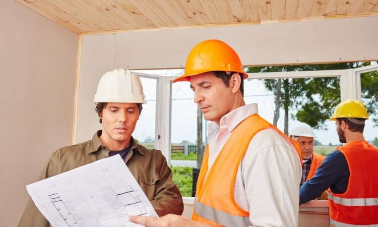 Professionnels étudiant le plan des travaux de rénovation énergétique d’un logement classé G